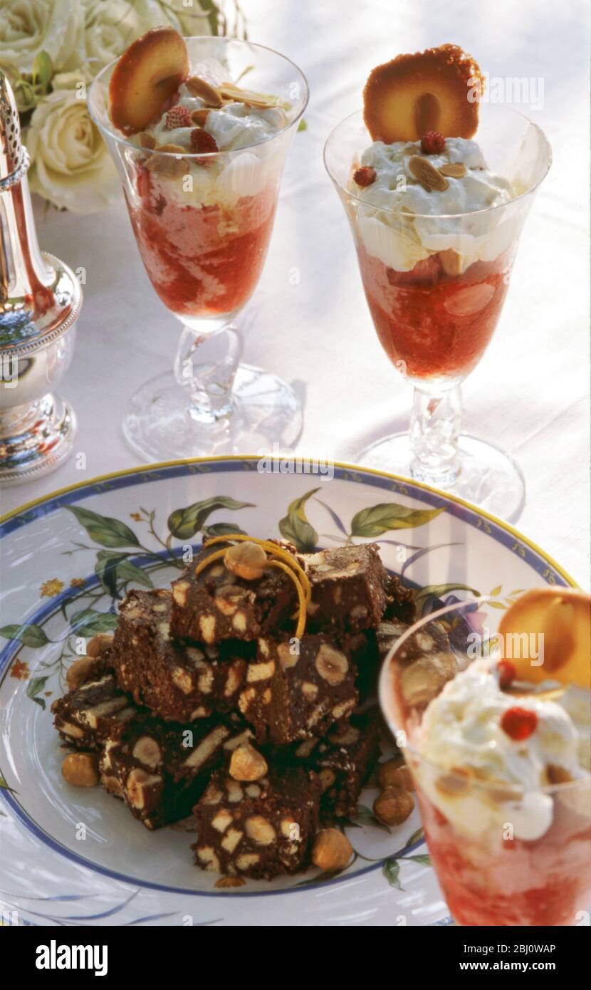 Erdbeer Champagner Sonnentöne mit kleinen Schokoladennuss Brownies als Dessert zu smart al fresco Sommer Lunch Party - Stockfoto
