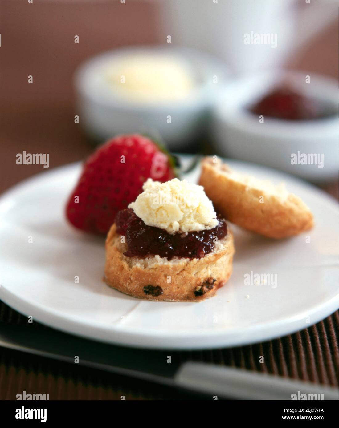 Klassische Scone mit gerinnter Sahne und Marmelade mit frischer Erdbeere serviert mit Afernoon Tee - Stockfoto