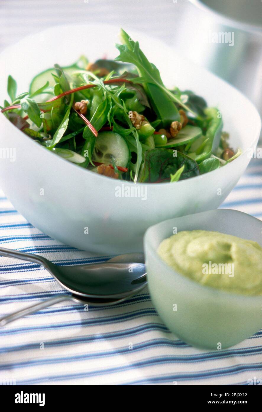 Gemischter Salat aus Rucola, Frisee, Baby Blätter, Lämmer Salat, Gurke und gehackte Walnüsse, um mit Dressing von Mayonnaise verde gekleidet werden, gemischt mit Stockfoto
