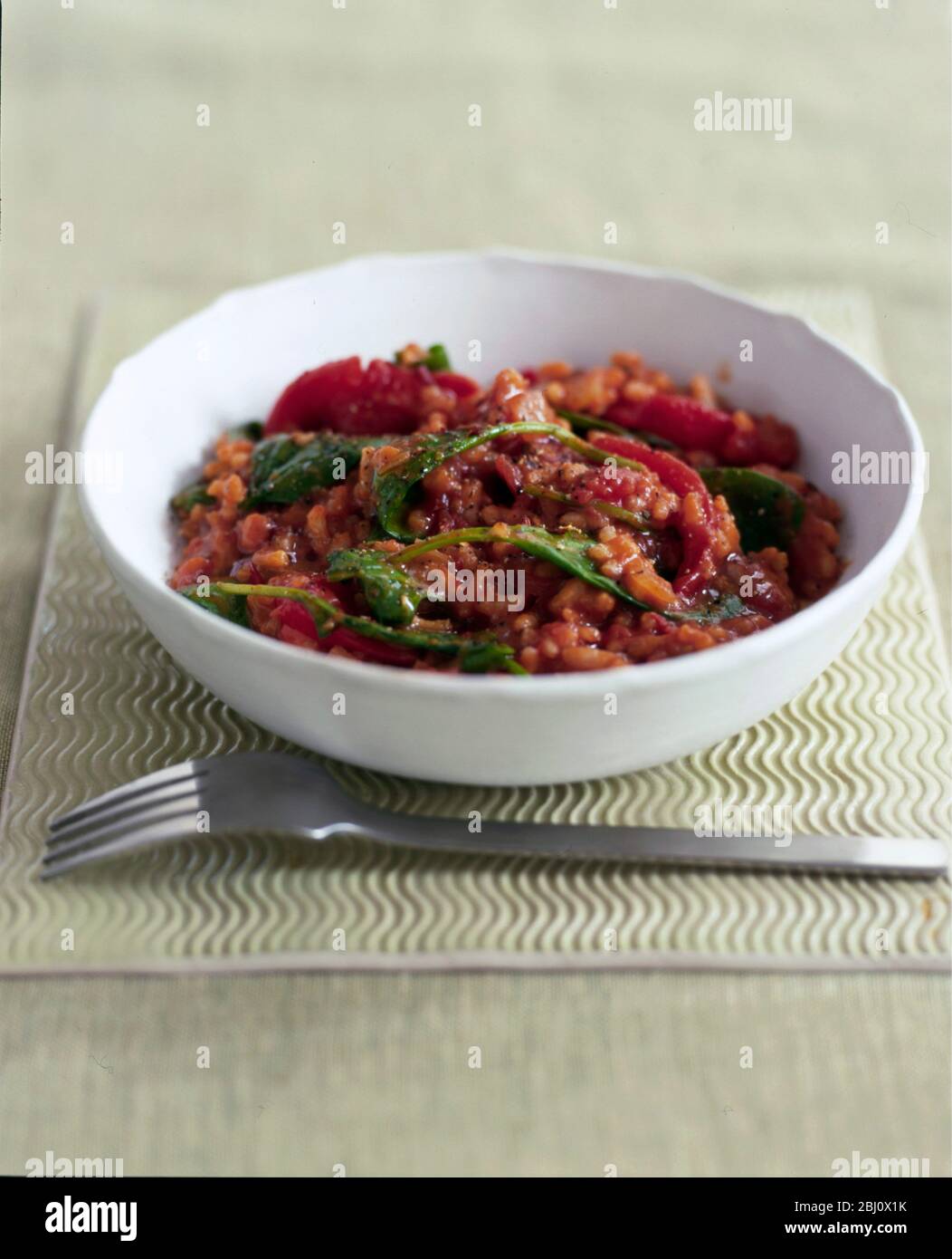 Rotes italienisches Risotto mit Pflaumentomaten und Basilikum - Stockfoto