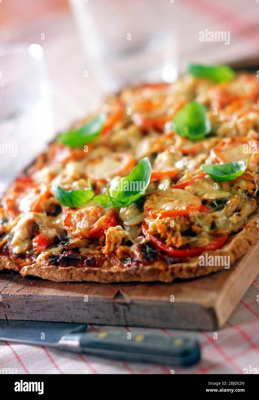 Tomaten- und Käsepizza auf Vollkornbasis mit Basilikumblättern - Stockfoto