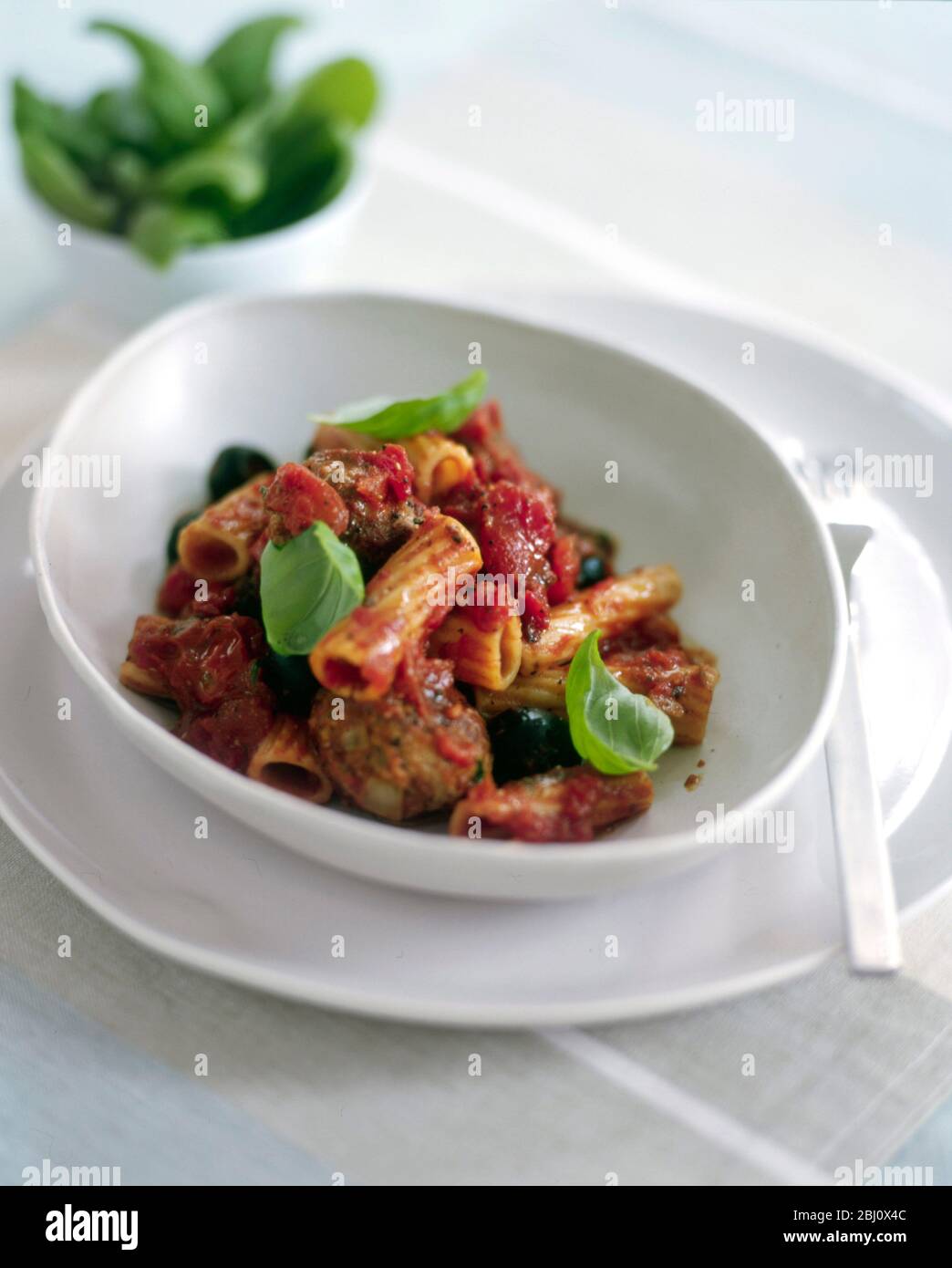 Servieren von Pasta mit Tomaten und schwarzer Olivensauce garniert mit Basilikum - Stockfoto