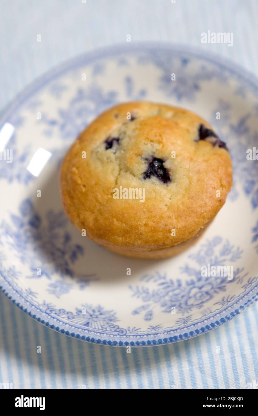 Frisch gebackener Heidelbeer Muffin auf blau gestreifter Serviette mit blau-weißem porzellan - Stockfoto