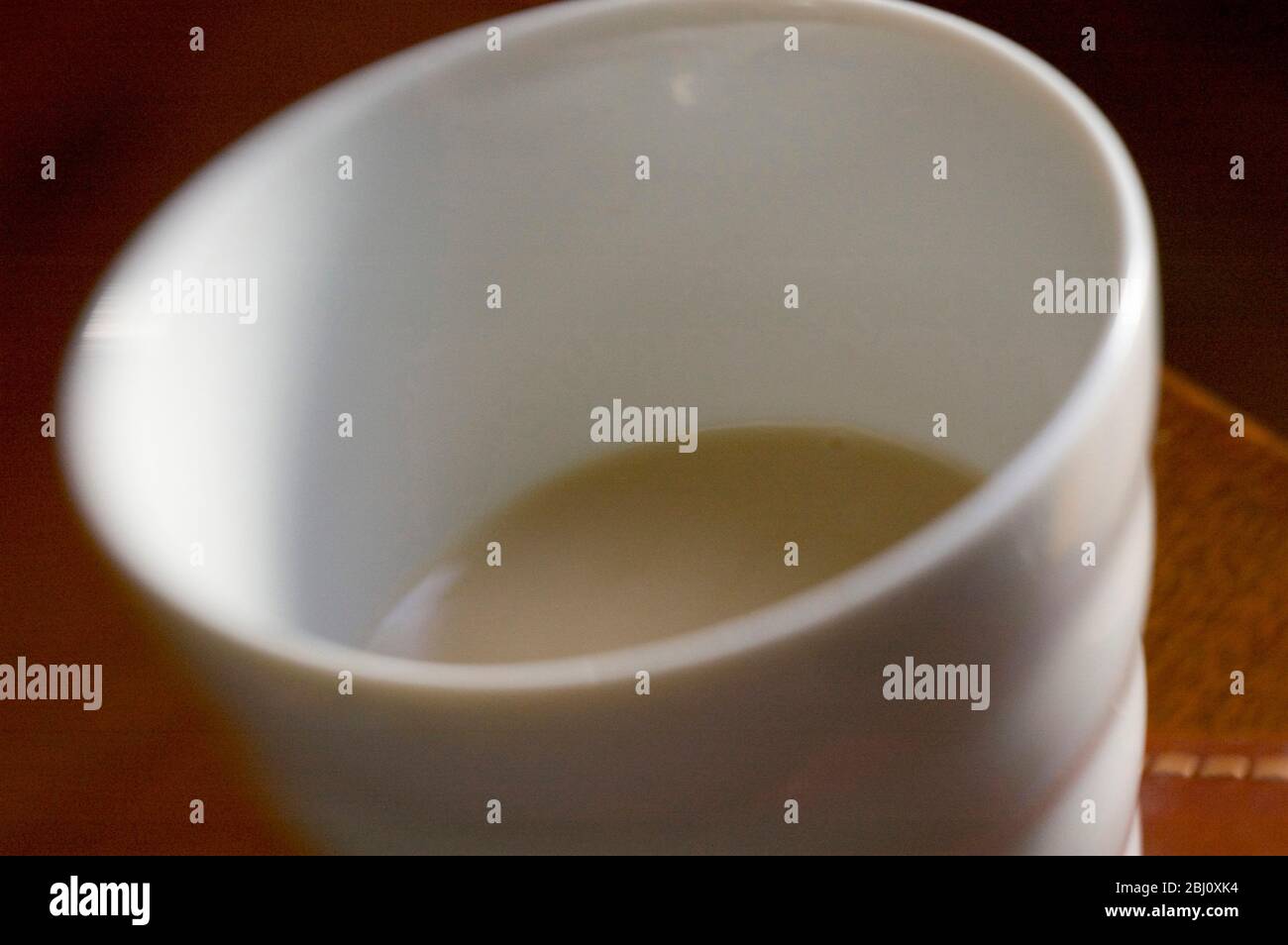 Halb leere (oder halb volle) Tasse os milchiger Tee, aufgenommen mit Lenssbaby-Linse für verschwommene Wirkung - Stockfoto