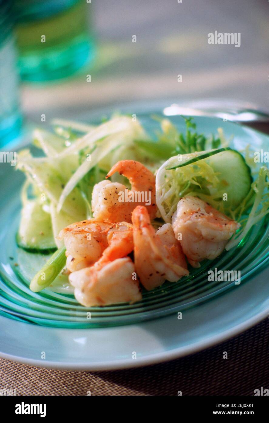 Jumbo Garnelen in würzigem Dressing mit Friseuesalat und Gurkensalat auf grünem Glasplatte - Stockfoto