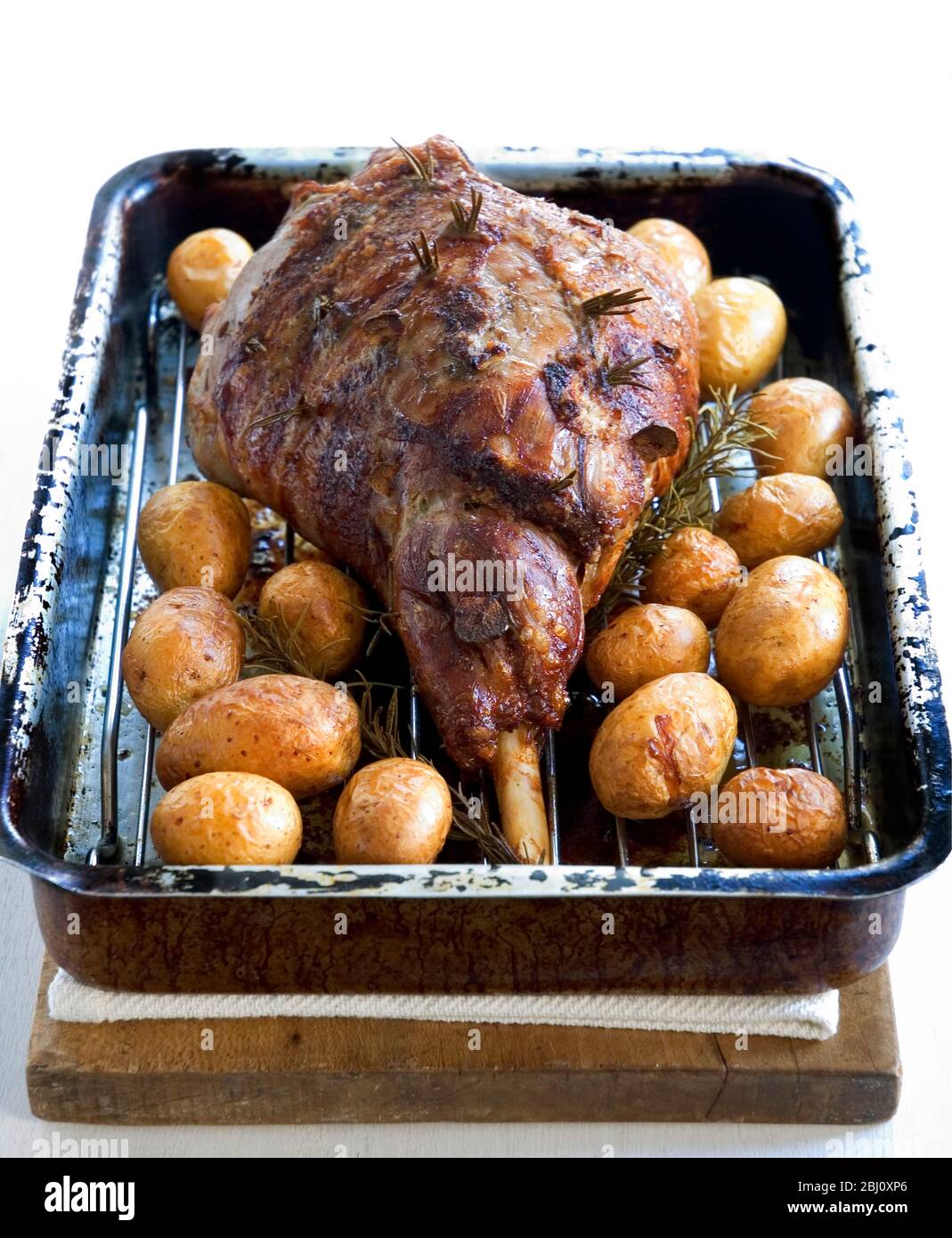 Lammkeule in der Bratform mit Braten neuer Kartoffeln in ihren Häuten. - Stockfoto