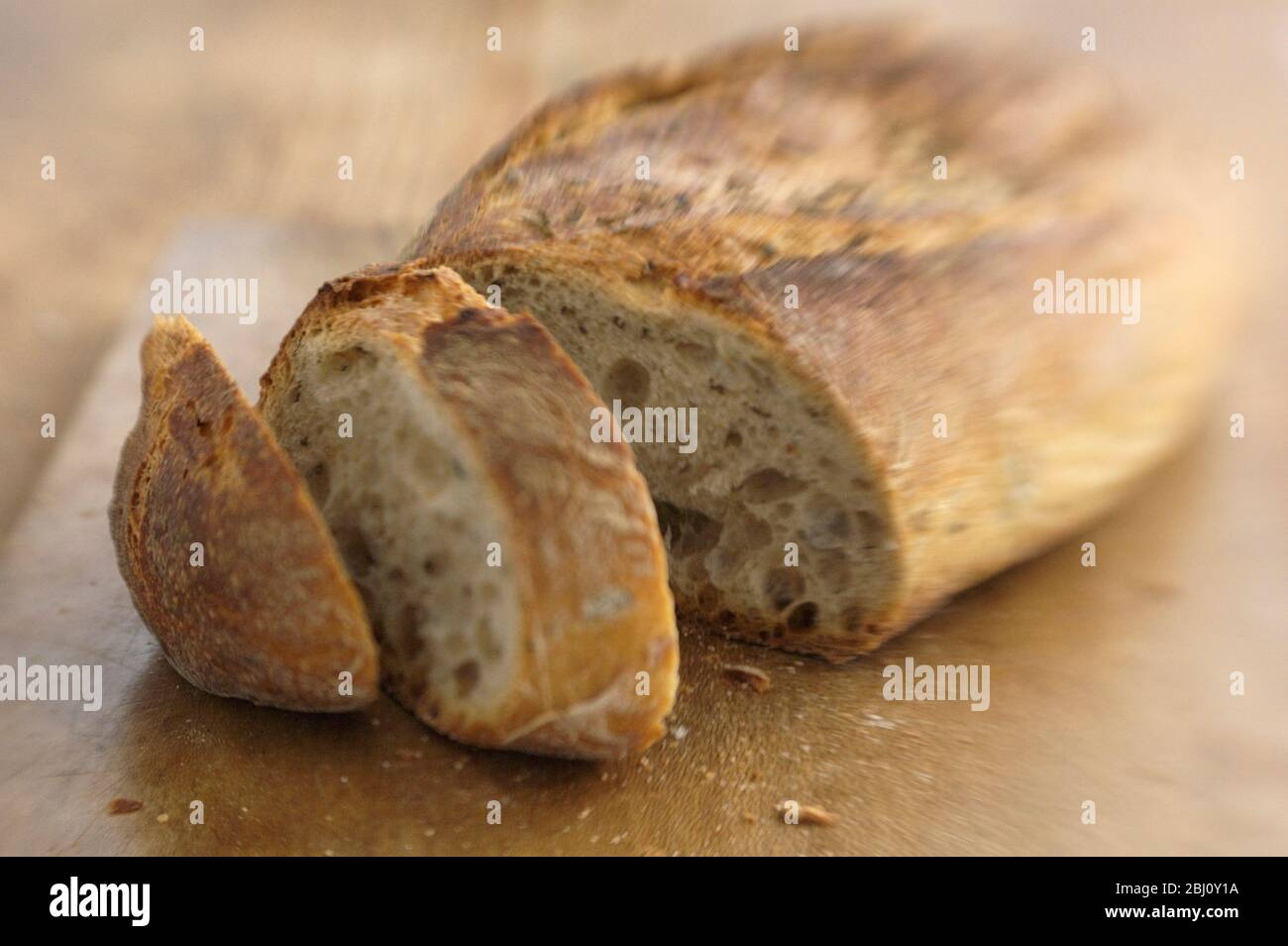 Italienisches Rosmarinsauerteigbrot aus Apulien, auf braunem Holzbrett, sho mit Lendenbaby-Linse für Blur-Effekt - Stockfoto