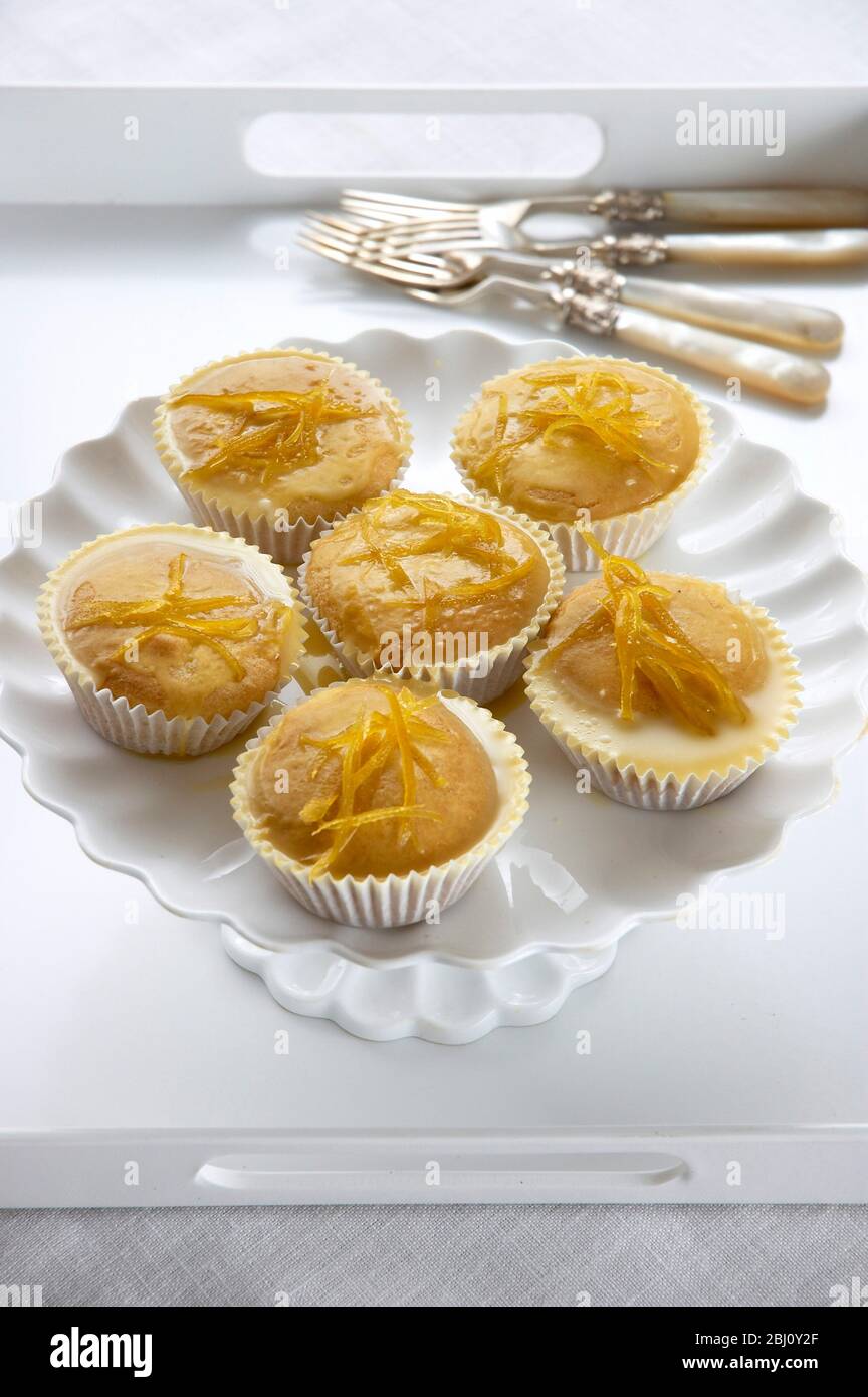 Zitronenmuffins mit Zitronenschale auf weißem Cakestand glasiert - Stockfoto