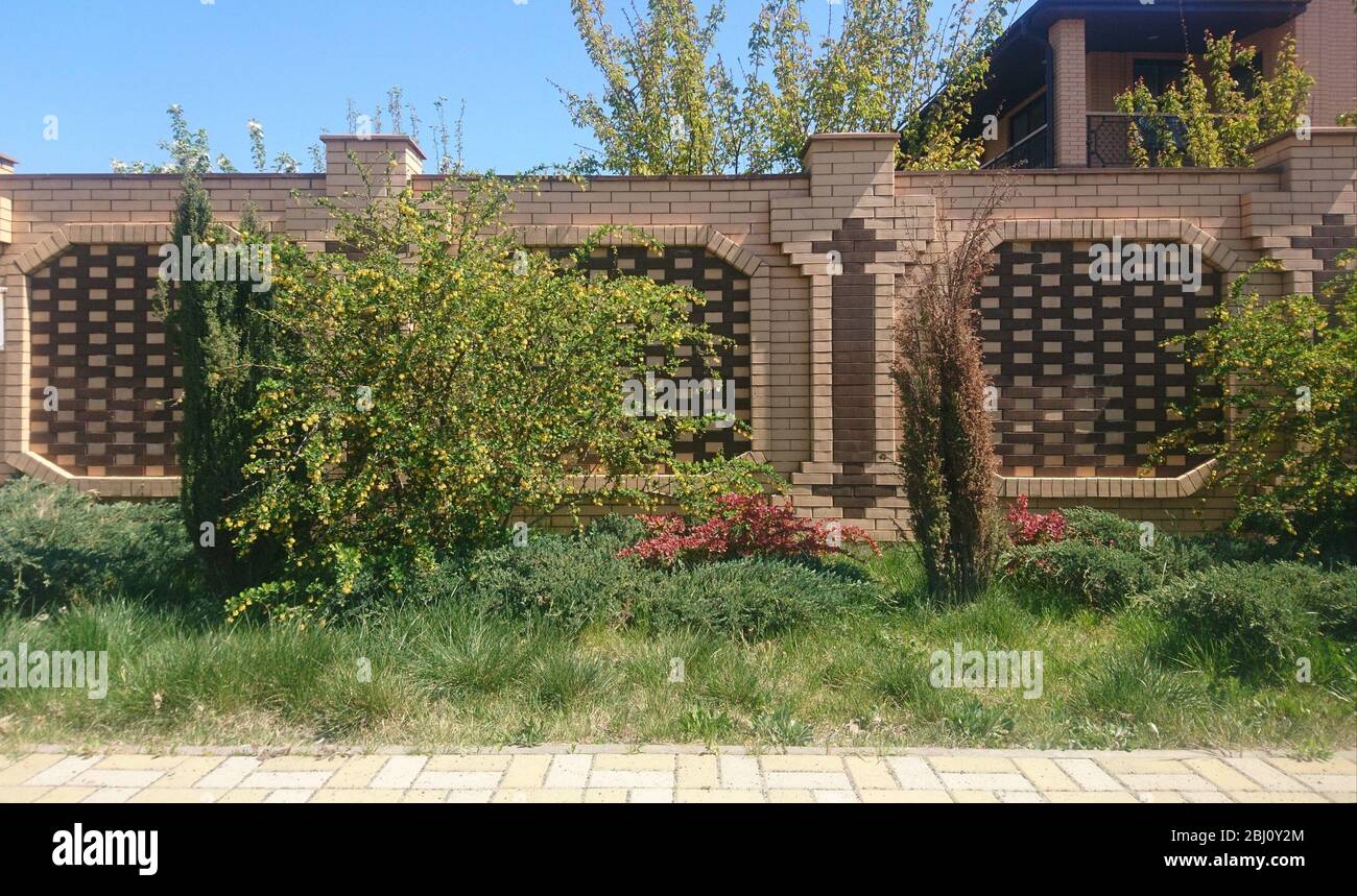 Dekorativer Rasen vor einem dekorativen Ziegel Zaun Stockfoto
