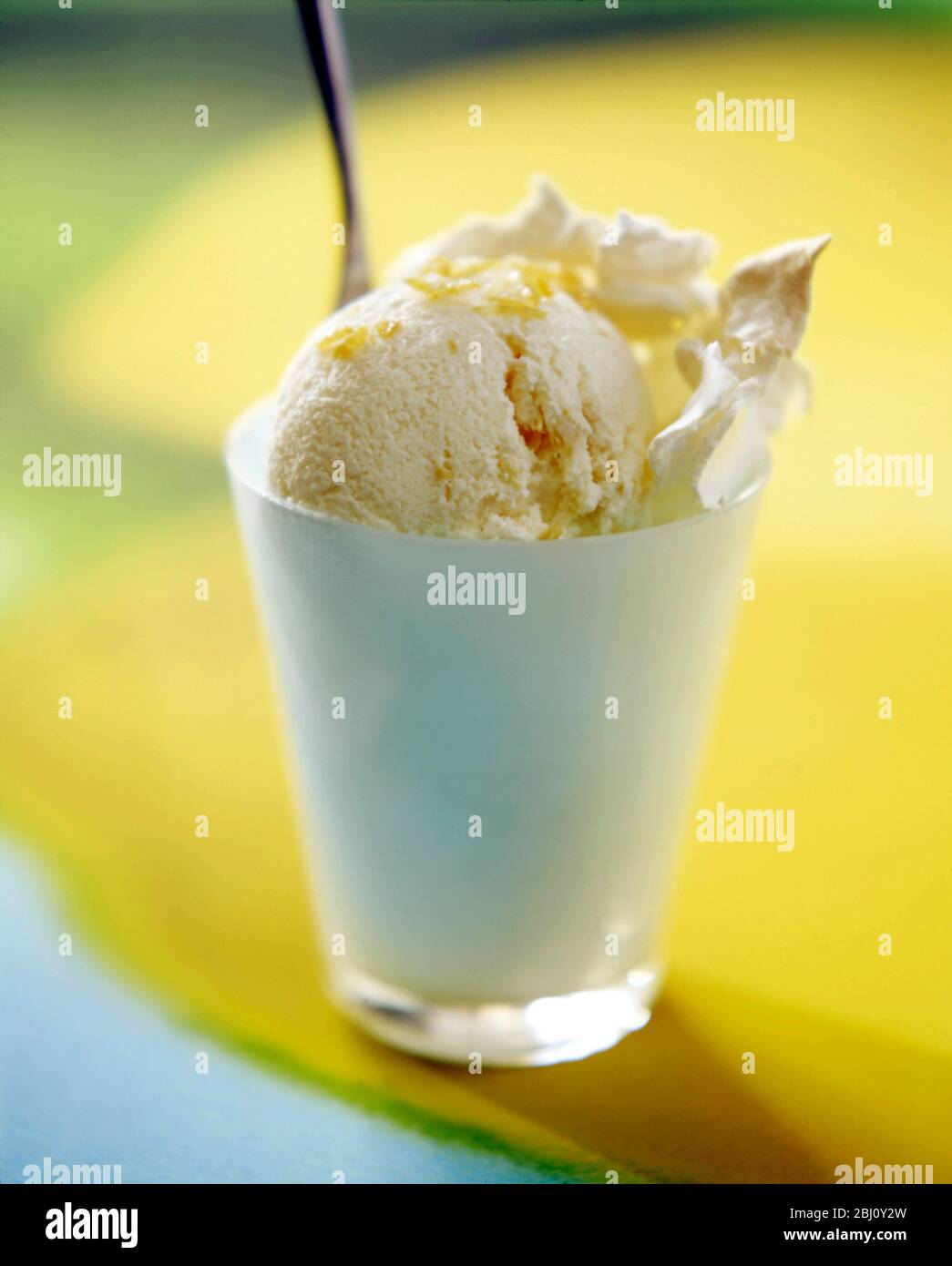 Zitroneneis mit zerquetschten Baiser in Milchglas auf Zitronenhintergrund - Stockfoto