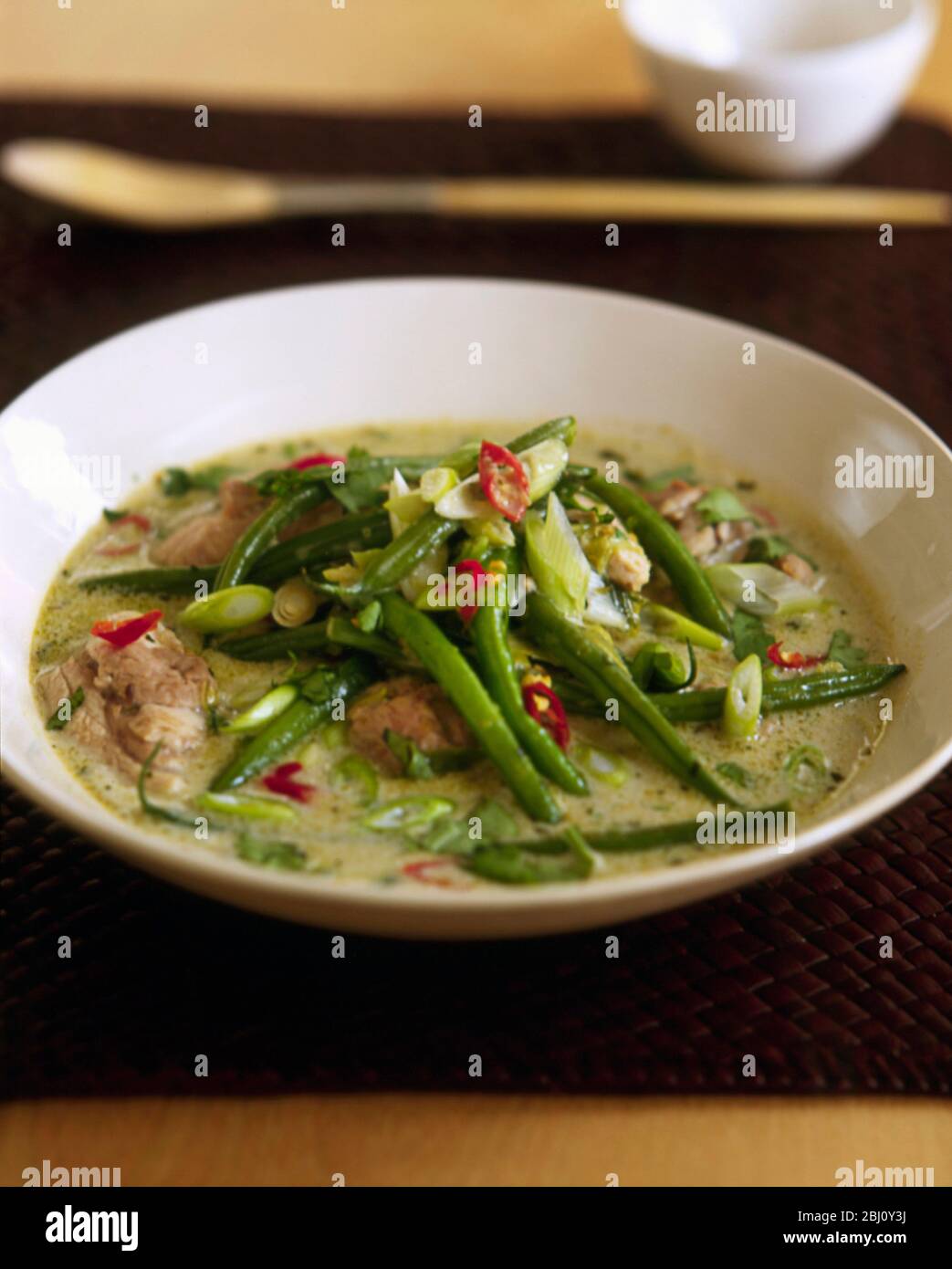 Grünes thai Chicken Curry in flacher Schüssel mit grünen Bohnen - Stockfoto