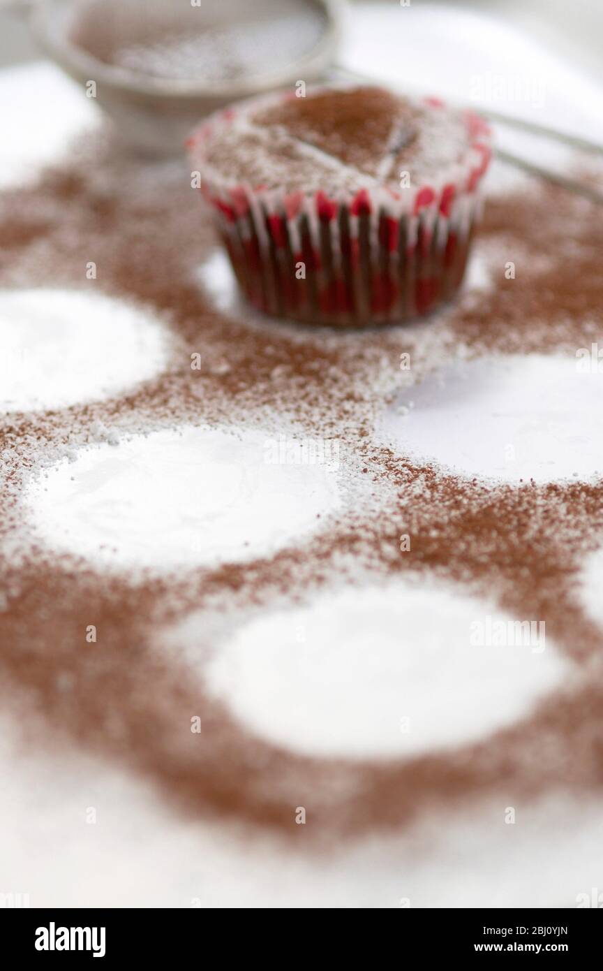 Schokoladige Muffins mit Kakaopulver abstauben - Stockfoto