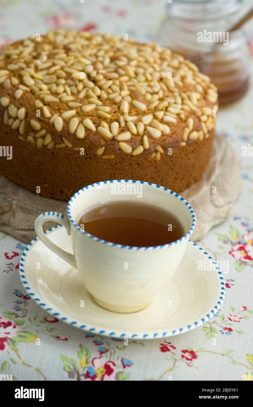 Tasse earl grauen Tee in Creme china ohne Milch und mit Pinienkerne gekrönt Kuchen im Hintergrund - Stockfoto