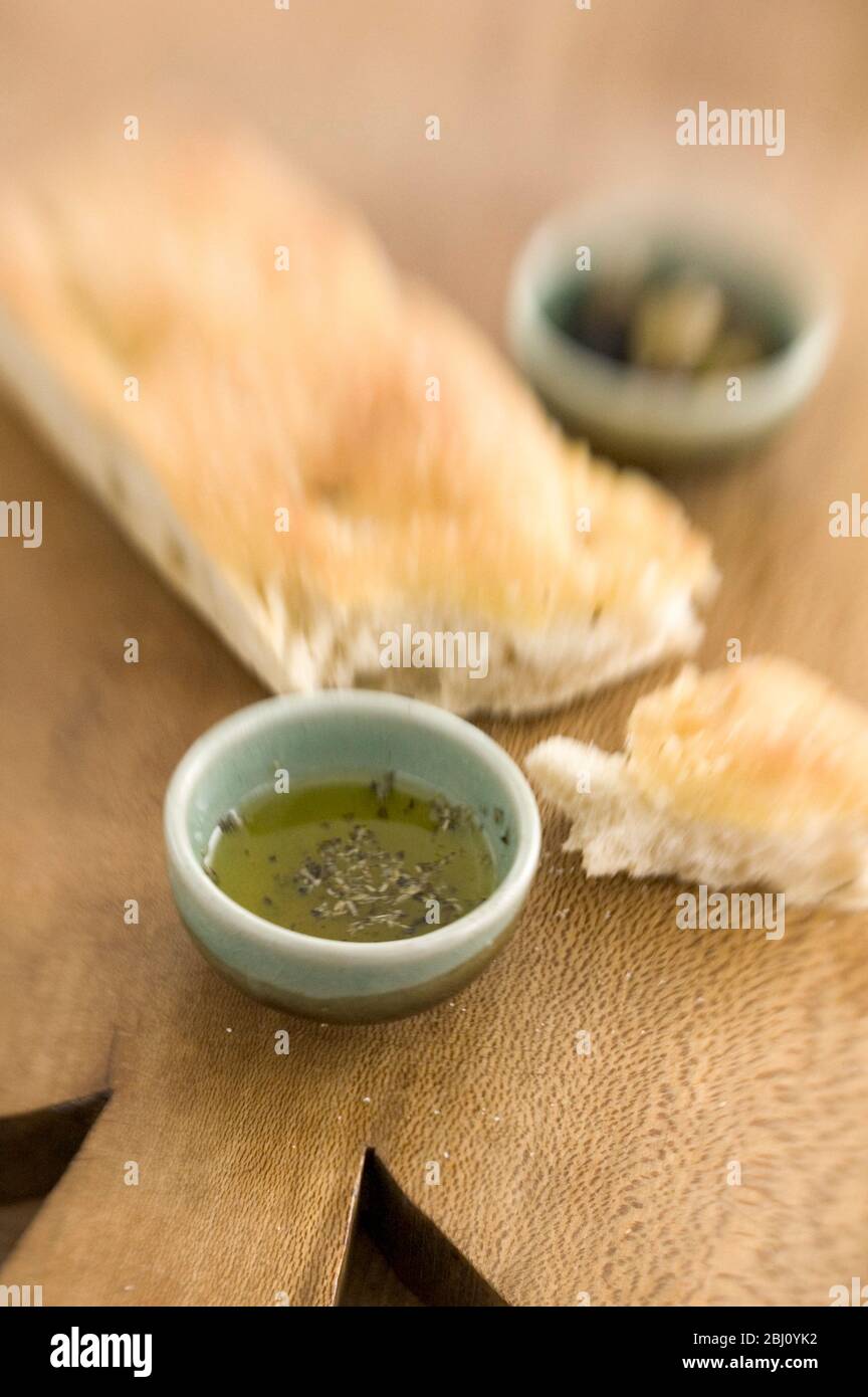 Olivenöl und Rosmarin Foccaccia Brot auf Holzbrett mit kleinen Schüsseln von einkerkerntem Olivenöl und ganze Oliven. Aufgenommen mit Objektiv für Lenskimitoren - Stockfoto