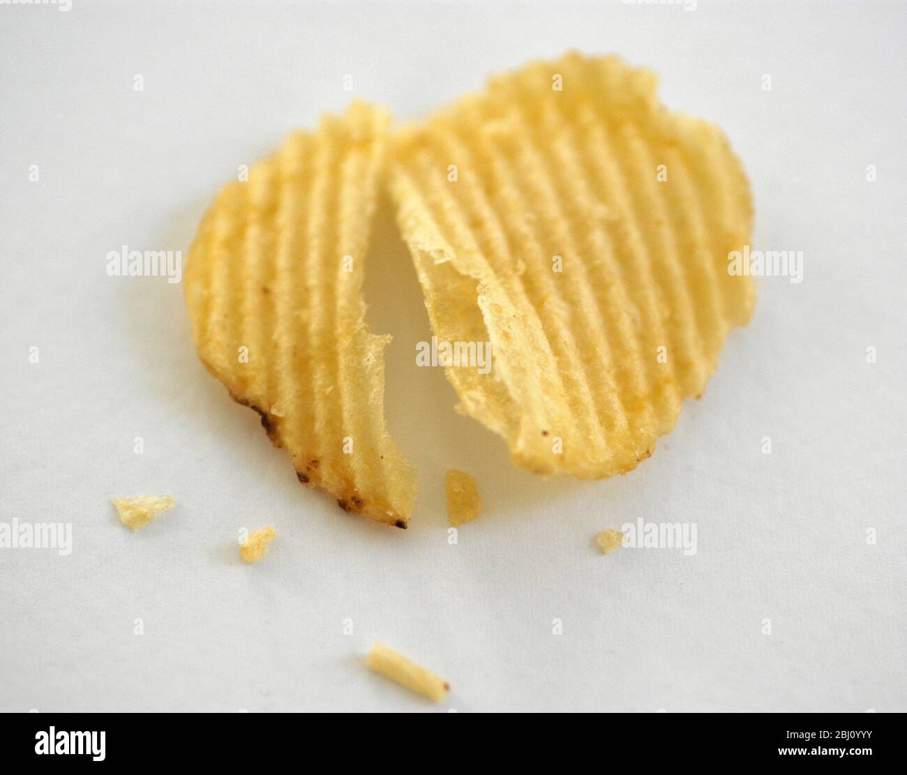 Zerkratztes Kartoffelchips auf weißem Hintergrund. Kurze Schärfentiefe - Stockfoto