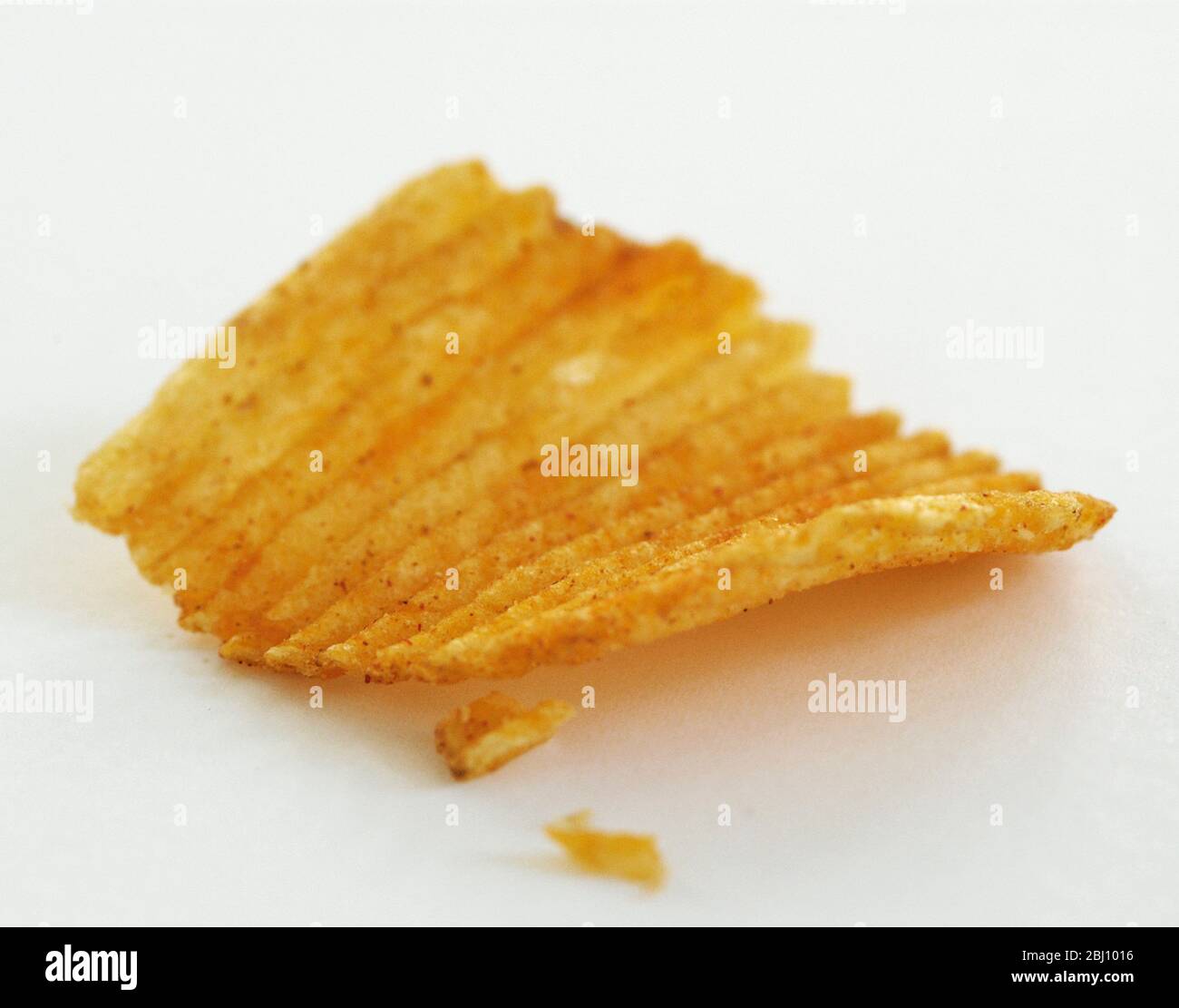 Zerkratztes Kartoffelchips auf weißem Hintergrund. Kurze Schärfentiefe - Stockfoto