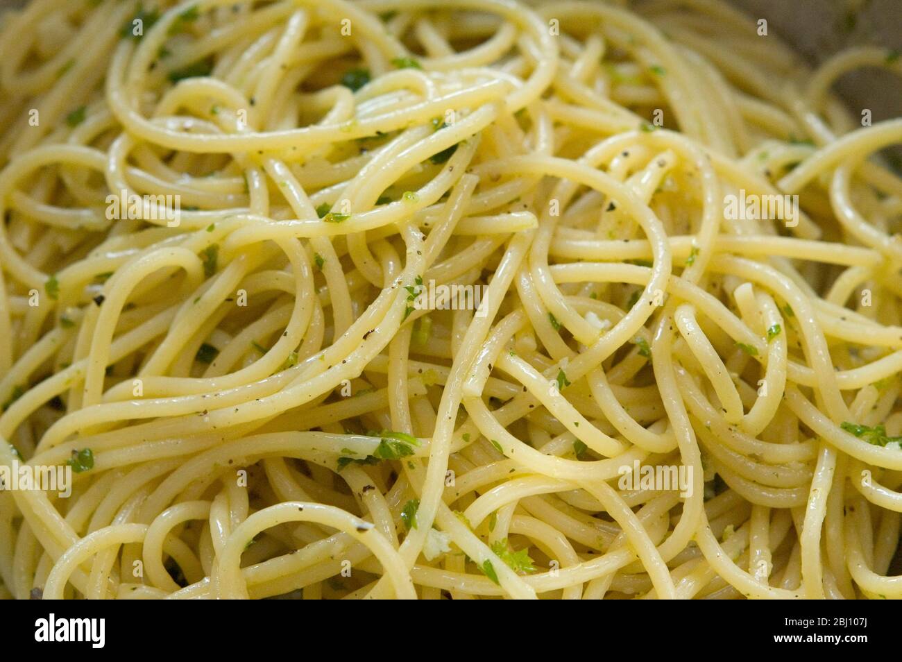 Spaghetti frisch gekocht und einfach mit Olivenöl, Salz und schwarzem Pfeffer und gehackte Petersilie gekleidet - Stockfoto