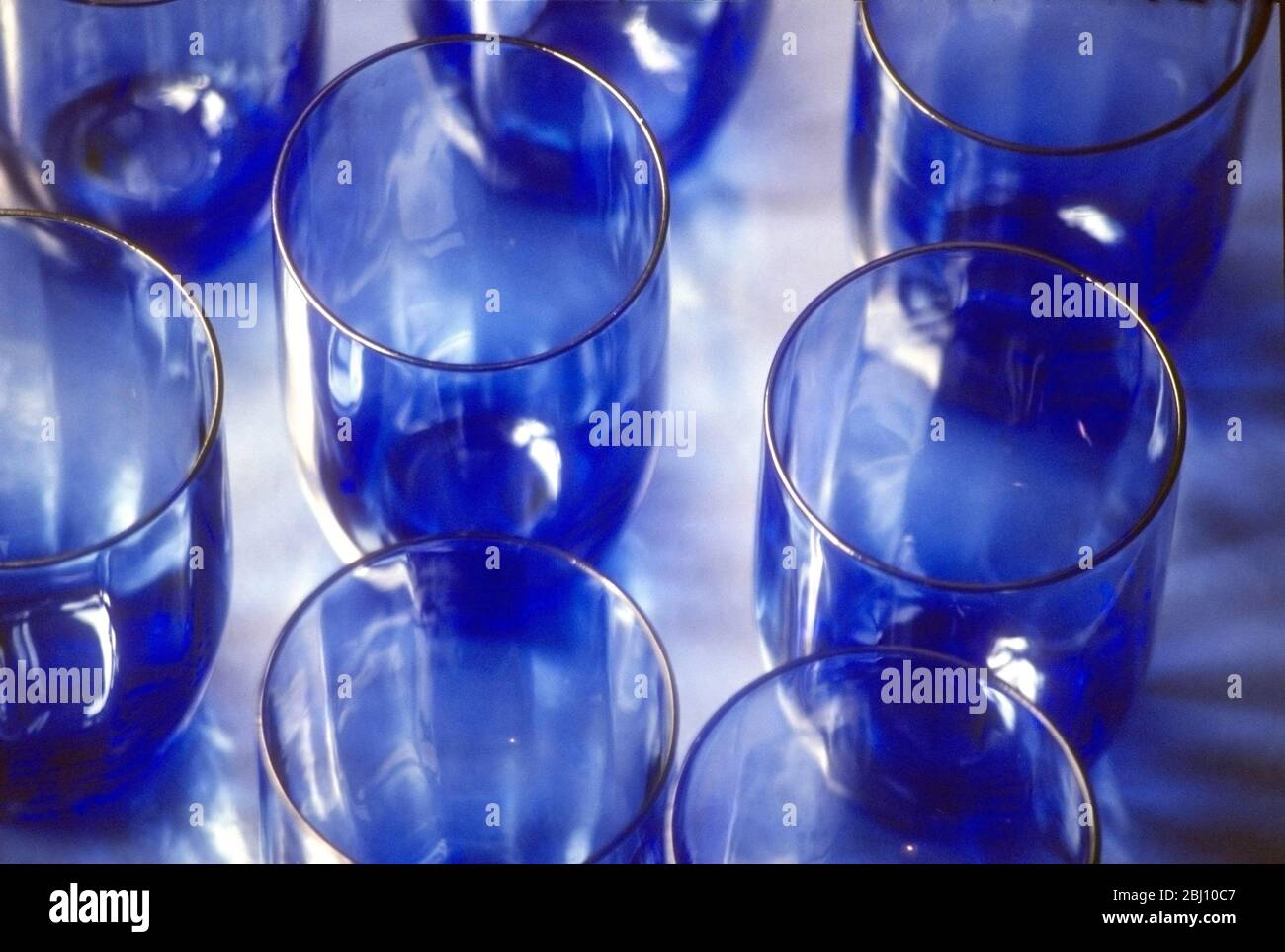 Eine Gruppe handgefertigter schwedischer Glas Trinkgläser auf semi-reflektierender Oberfläche - Stockfoto