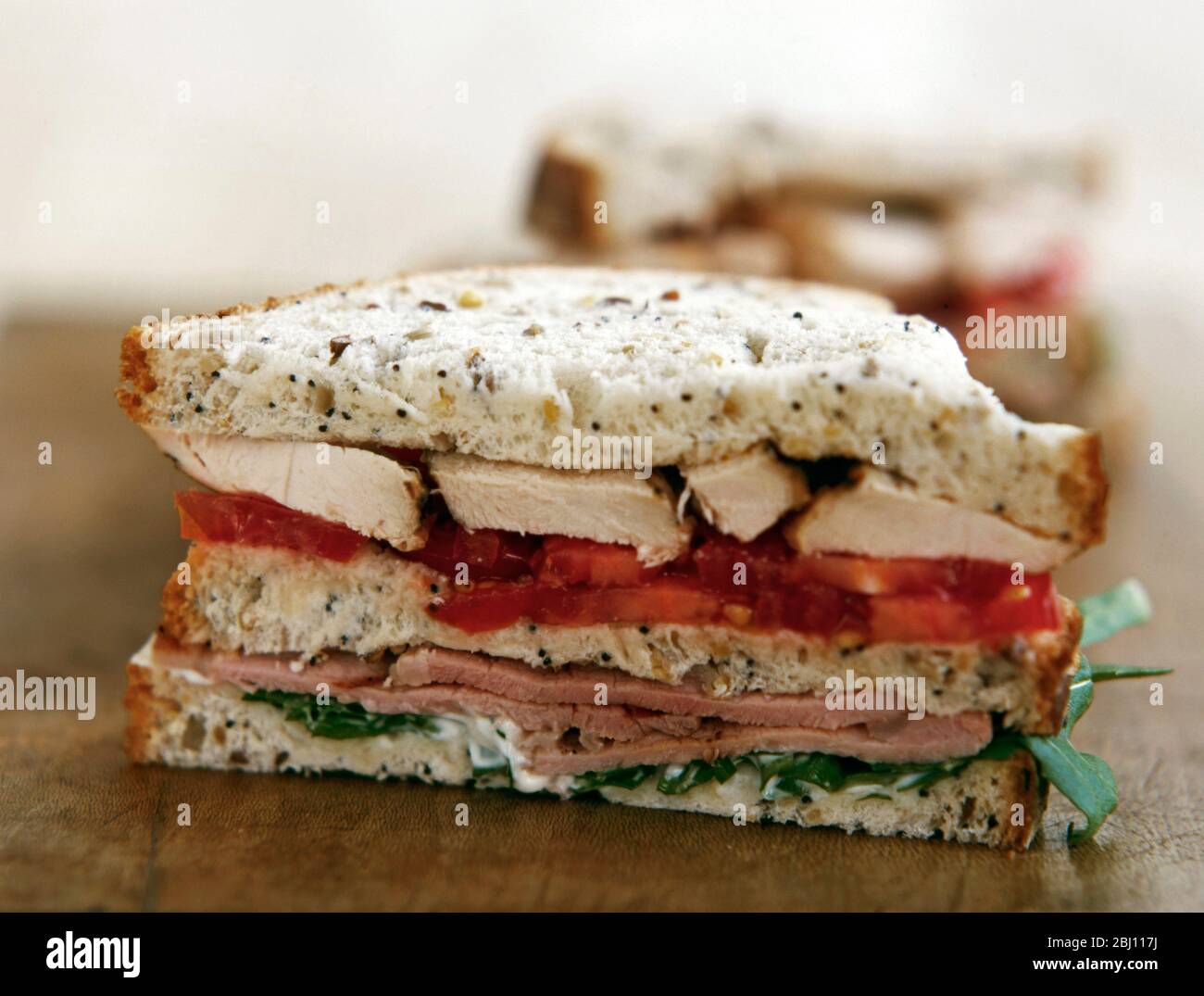 Sandwich aus Huhn, Tomaten, Schinken und Salat auf Brot mit Sämerei - Stockfoto