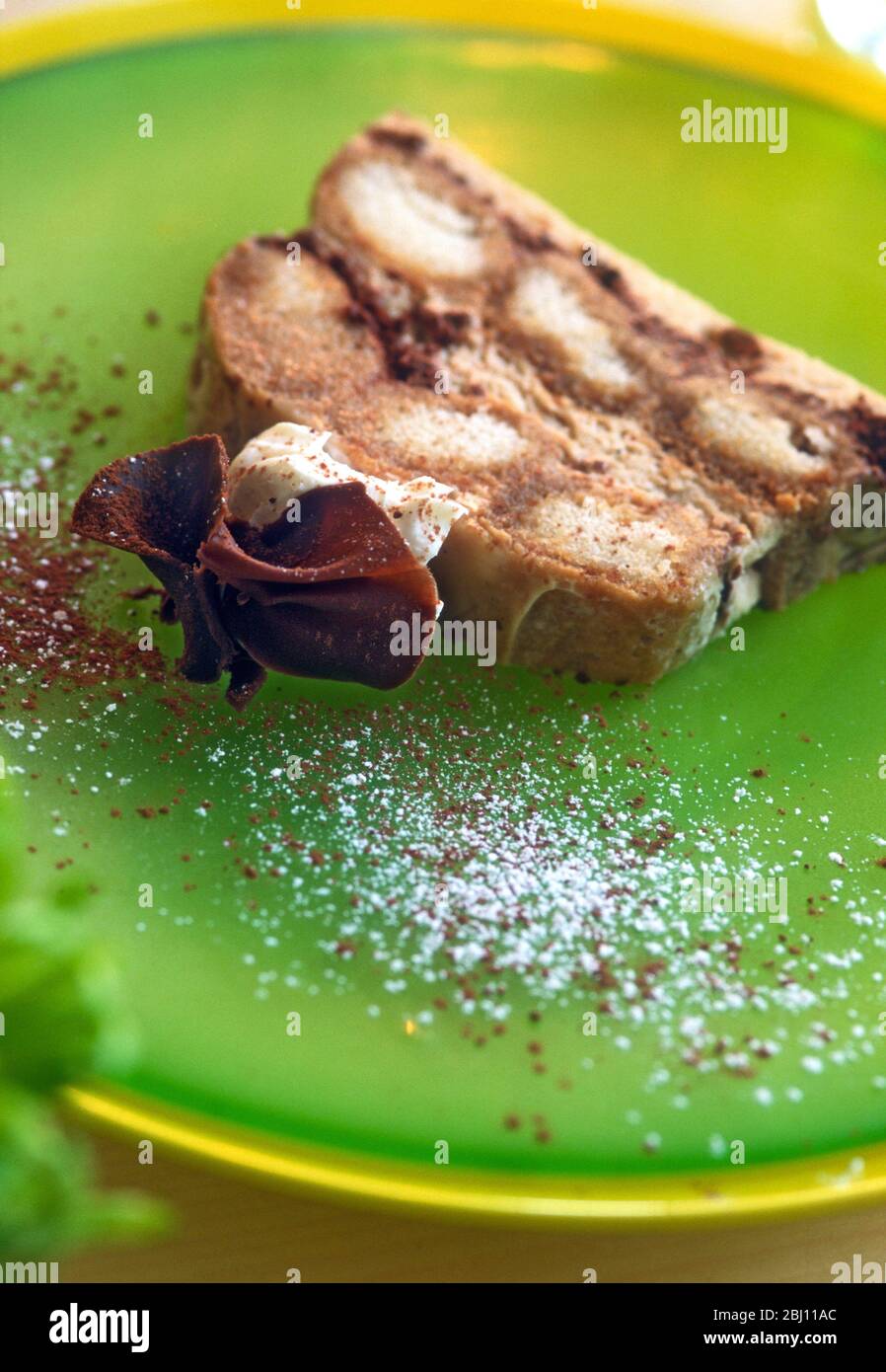 Scheibe Schokolade Baiser Dessert auf grünem Glasplatte, mit Puderzucker bestäubt. - Stockfoto