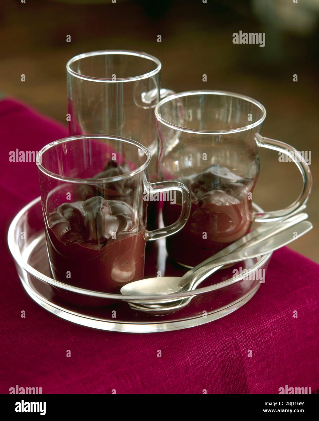 Drei feine Glaskrüge mit Schokoladendessert auf Glastablett - Stockfoto