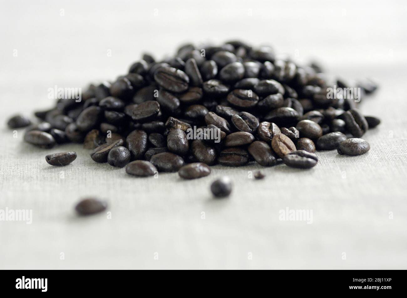 Kleiner Haufen dunkel gerösteter Kaffeebohnen auf Leinwand - Stockfoto