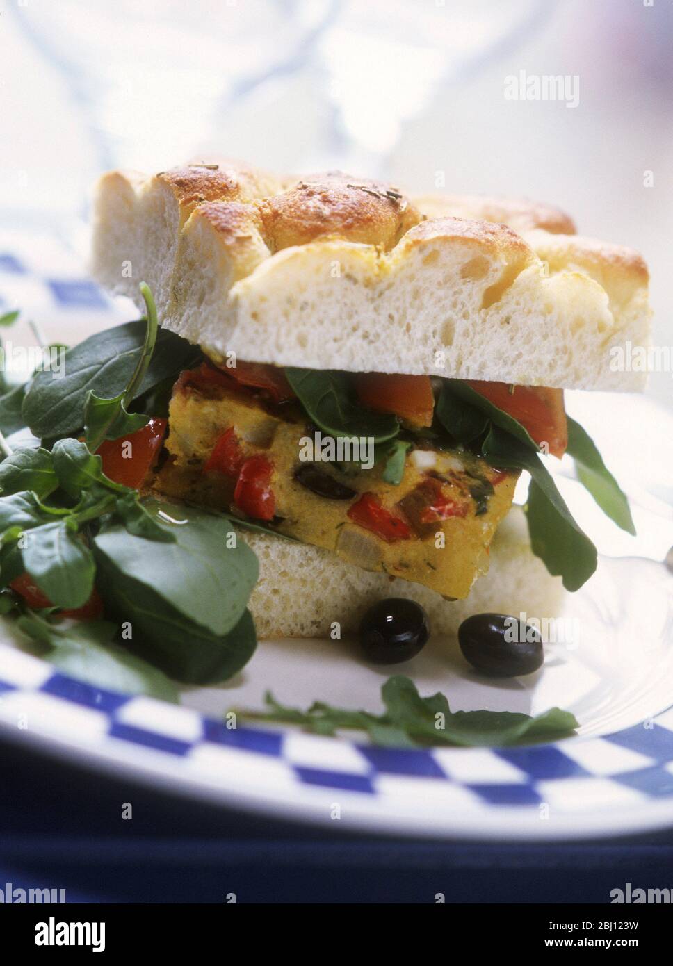 Sandwich von spanischen Omelette (Frittata) in Foccacia-Brot mit Rucola-Salat und schwarzen Oliven - Stockfoto