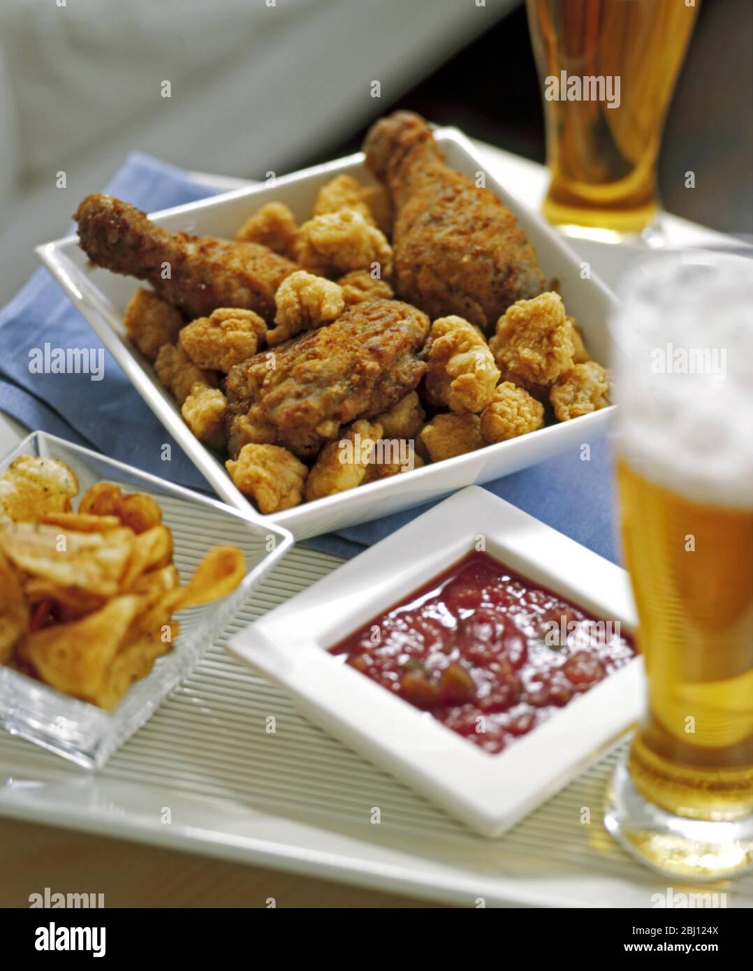 Zwangloses Menü aus gebratenem Huhn, Chips, Tomatensalsa und Bier - Stockfoto