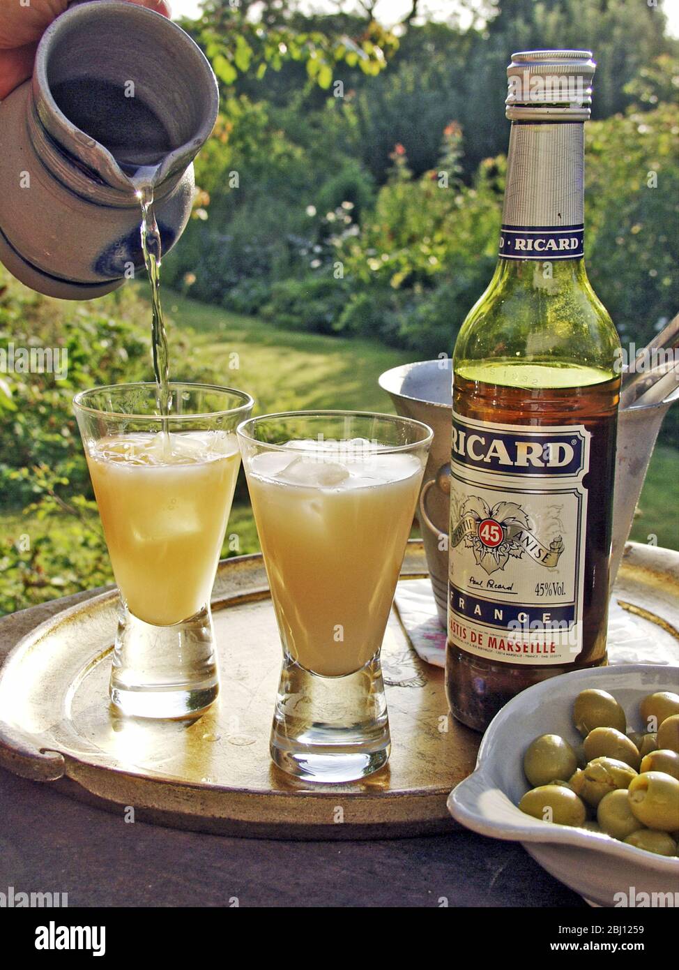 Zwei Gläser pernod-Getränk, das in der Abendsonne gegossen wird - Stockfoto