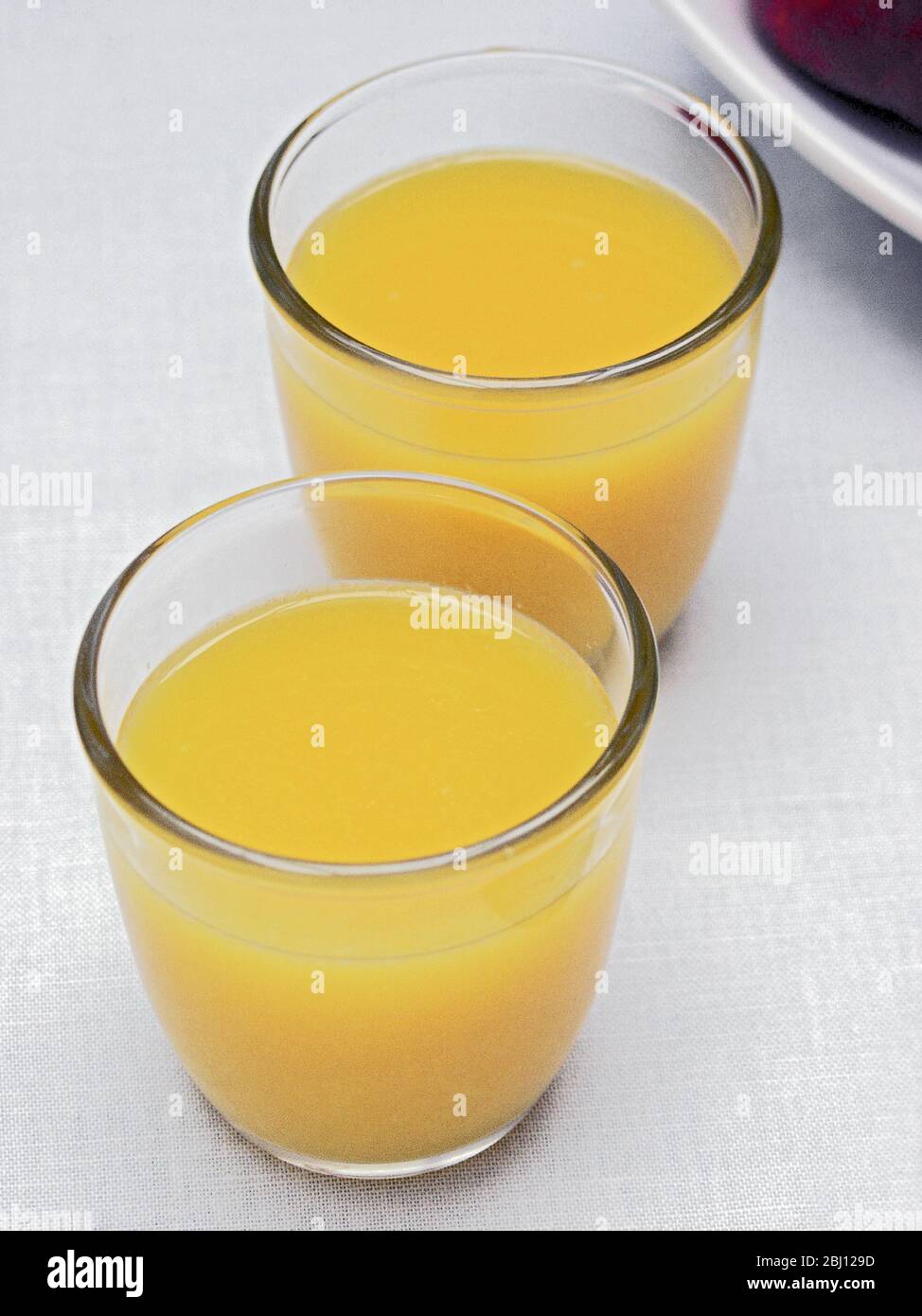 Zwei Gläser Orangensaft auf weißem Tischtuch - Stockfoto