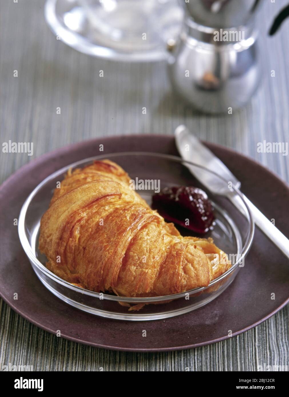 Croissant auf Glasteller mit Kirschmarmelade - Stockfoto