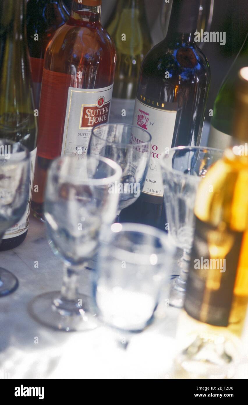 Gläser und Weinflaschen auf Tisch bei Sonnenschein und Schatten - Stockfoto