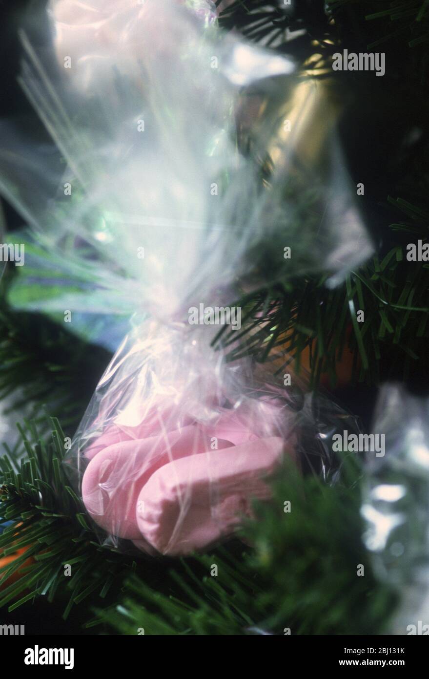 Süßigkeiten in einem Netzbündel gebunden und als Dekoration an einem Weihnachtsbaum hängend - Stockfoto