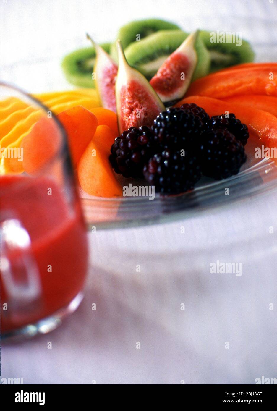 Attraktiv angerichtet geschnittenes und zubereitetes Obst auf Glasplatte, serviert als Dessert - Stockfoto