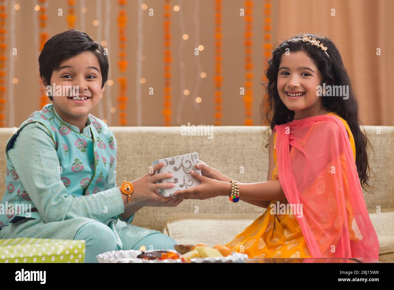 Kleiner Bruder und Schwester halten ein Geschenkpaket auf die Gelegenheit von Rakshabandhan Stockfoto