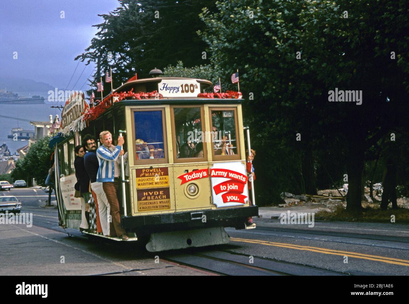 Passagiere an Bord einer aufsteigenden Cable Car-Linie, Powell-Hyde Line, San Francisco, Kalifornien, USA 1973. In diesem Jahr wurde das berühmte öffentliche Verkehrsnetz zum 100. Mal in den Mittelpunkt gestellt, und die Seilbahnen waren mit Schildern, Aschen und amerikanischen Flaggen geschmückt. Stockfoto