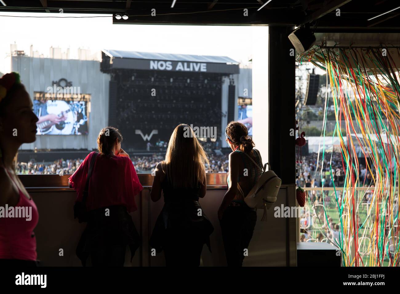 Freunde auf einem Balkon mit Blick auf die Hauptbühne des Musikfestivals EDP Nos Alive, in Alges, Lissabon, Portugal. Stockfoto