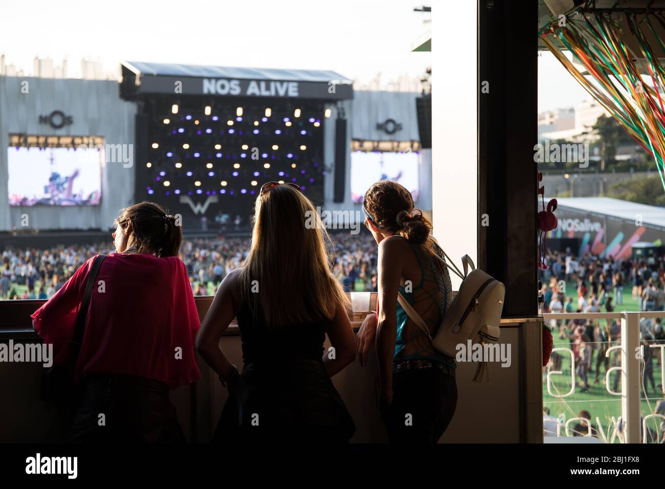 Freunde auf einem Balkon mit Blick auf die Hauptbühne des Musikfestivals EDP Nos Alive, in Alges, Lissabon, Portugal. Stockfoto