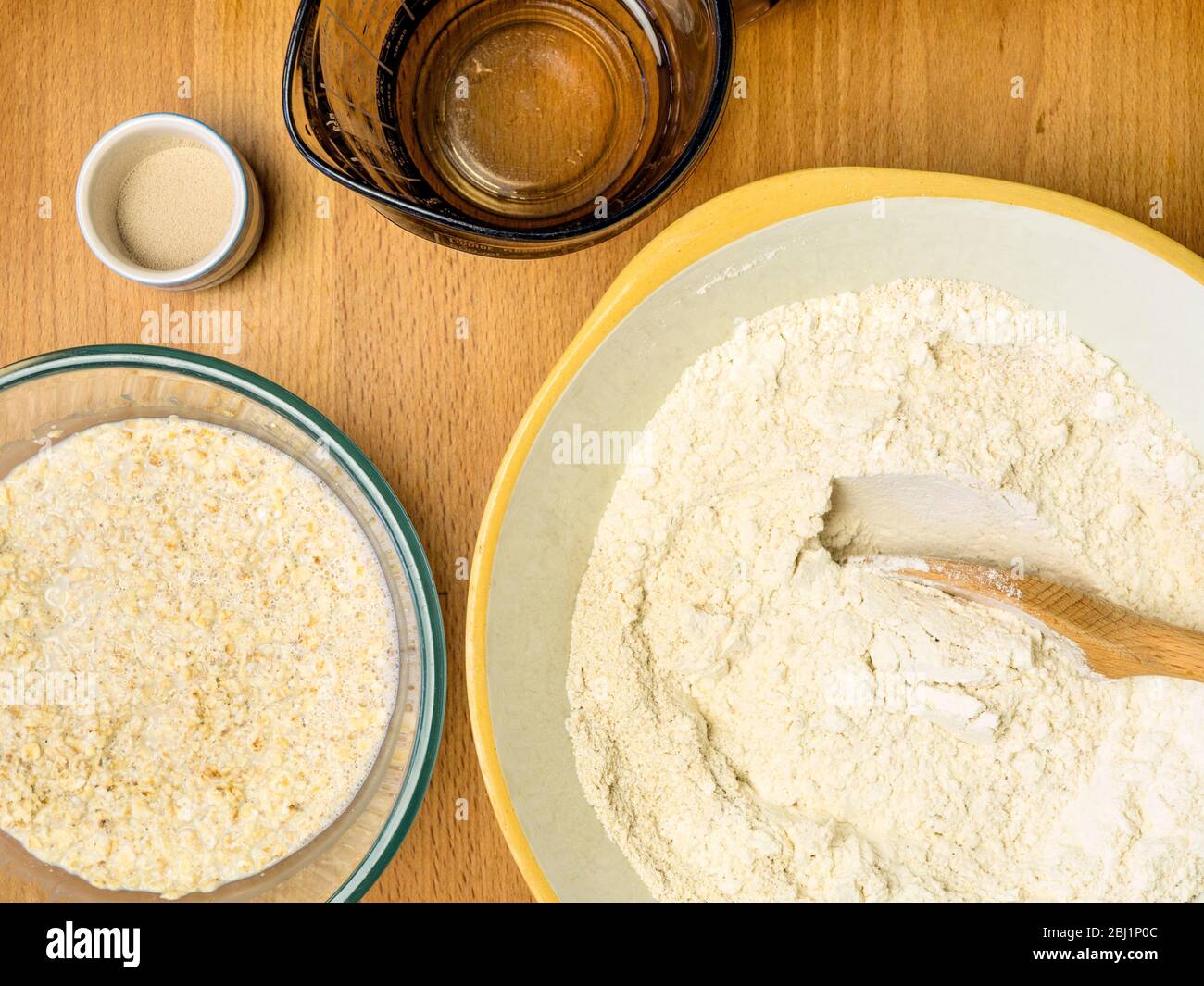 Hafermehl mit kräftigem Weißbrotmehl mischen und Haferflocken in Hafermilch mit Hefe und Wasser zur Herstellung von Haferbrot einweichen Stockfoto
