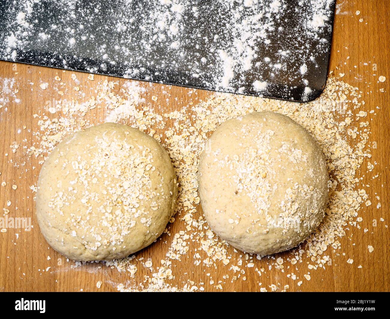 Zwei Runden Haferbrotteig in Hafer mit einem bemehlten Backblech auf einem Küchentisch gerollt Stockfoto