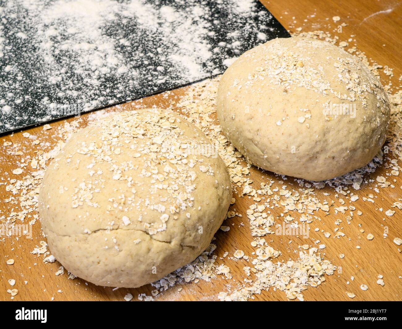 Zwei Runden Haferbrotteig in Hafer mit einem bemehlten Backblech auf einem Küchentisch gerollt Stockfoto