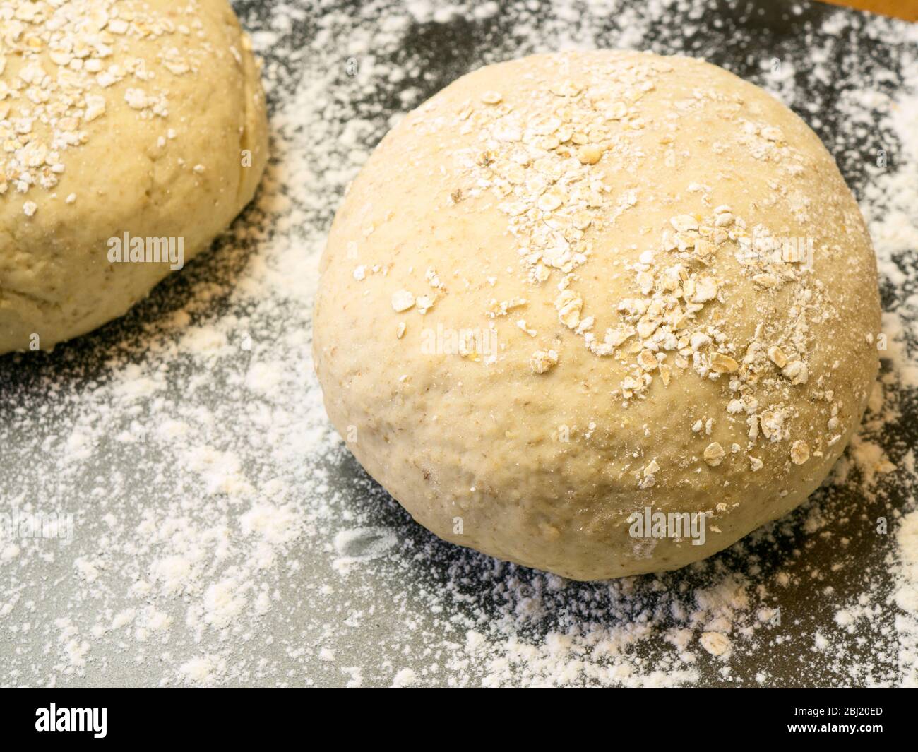 Zwei Runden Haferbrotteig in Hafer auf einem bemehlten Backblech auf einem Küchentisch gerollt Stockfoto