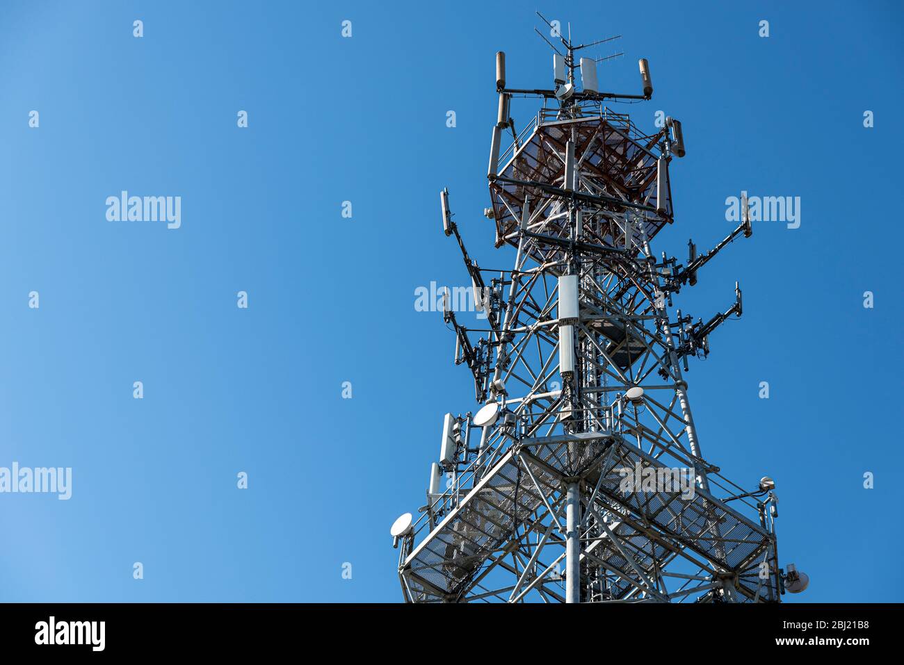 Oben auf dem Mobilfunkturm gegen blauen Himmel. Antenne für Mobiltelefone Telekommunikation verwendet. Stockfoto