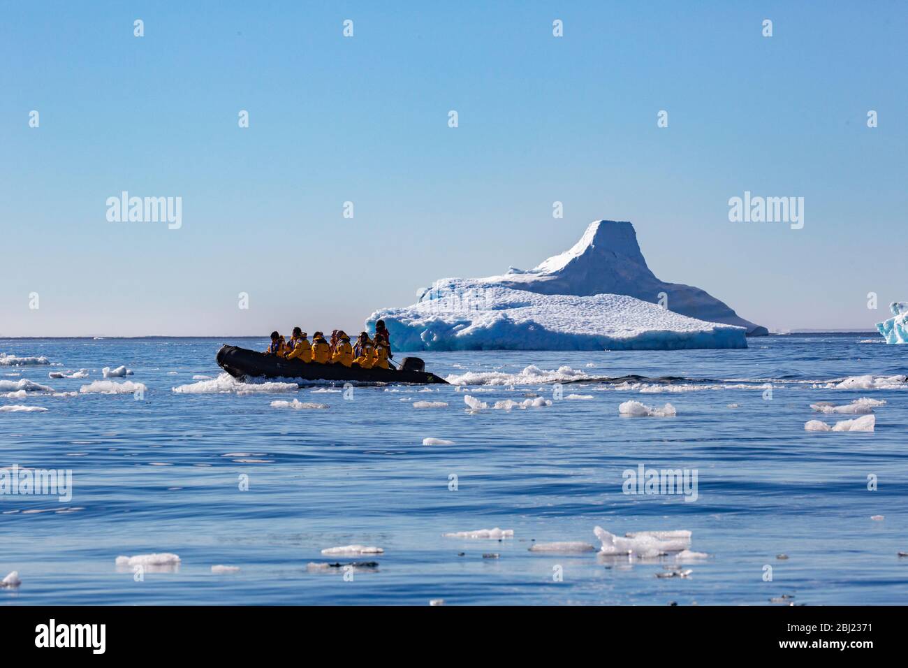 Eine Gruppe von Menschen, die in einem Zodiac Beiboot sitzen und durch Eisscholle auf der Antarktis segeln. Stockfoto