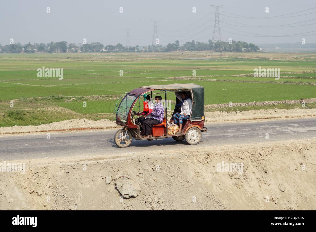 Jaflong / Bangladesch - 28. Januar 2019: Eine Gruppe von Menschen, die im Tuk Tuk in der ländlichen Landschaft mit schönen Reisfeldern im Hintergrund reisen Stockfoto