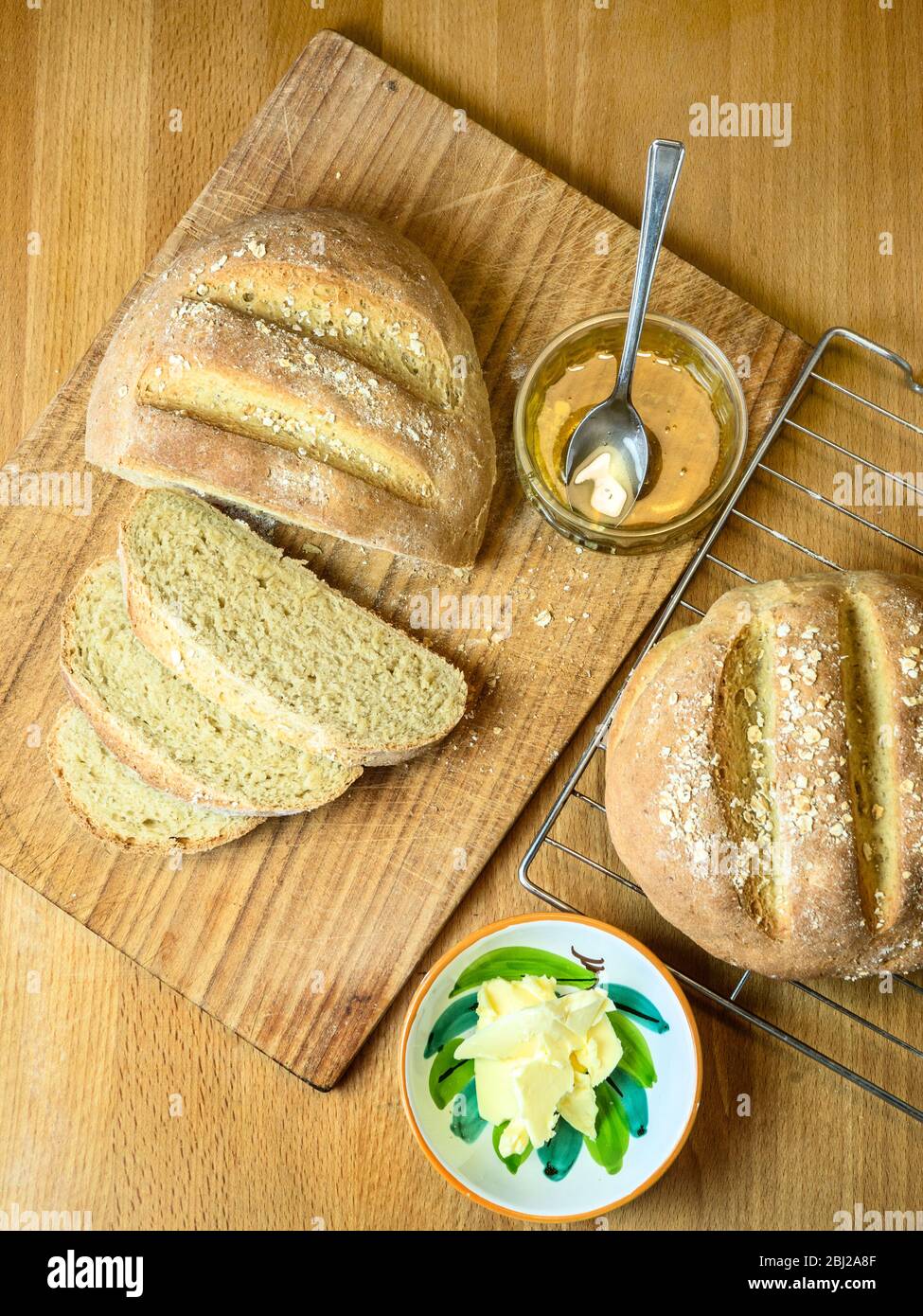 Frisch gebackenes Haferbrot mit Weißbrotmehl und Hafermehl, gekrönt mit Haferflocken mit Honig und nicht Milchaufstrich Stockfoto