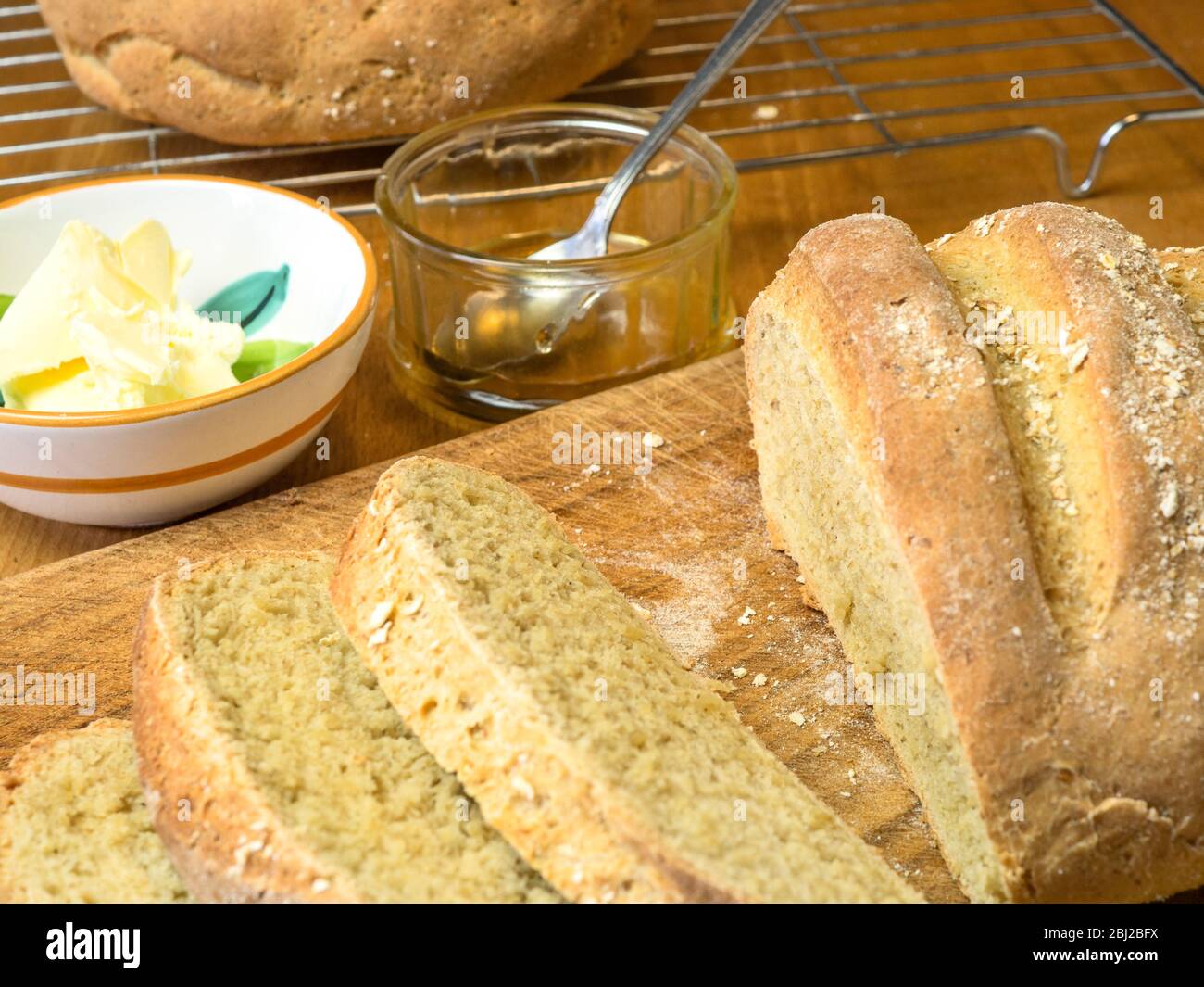 Frisch gebackenes Haferbrot mit Weißbrotmehl und Hafermehl, gekrönt mit Haferflocken mit Honig und nicht Milchaufstrich Stockfoto