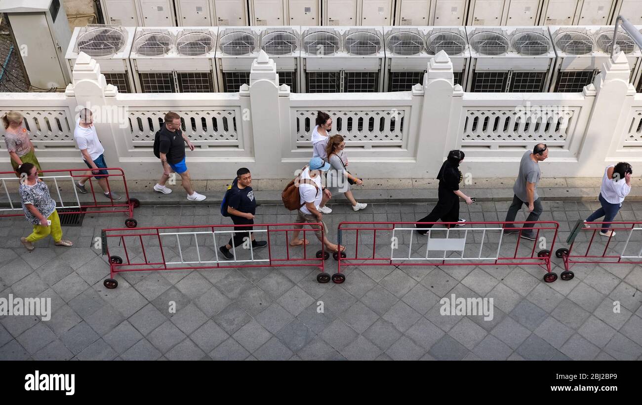 BANGKOK/THAILAND - FEBRUAR 15 2020: Touristen gehen entlang Straßenpflaster vorbei an traditionellen Zaun weiße Wand mit Ornamenten in der Nähe rotierenden Conditioner obere Ansicht Zeitlupe am 15. Februar in Bangkok Stockfoto