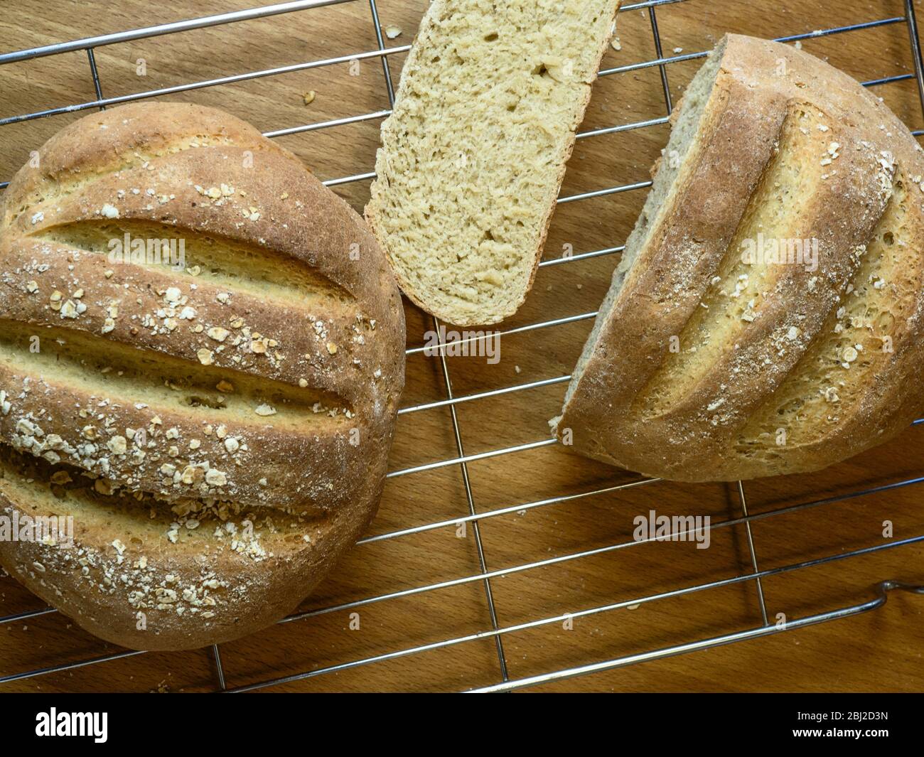 Frisch gebackenes Haferbrot mit Weißbrotmehl und Hafermehl auf einem Drahtscheiben mit Haferflocken überzogen Stockfoto