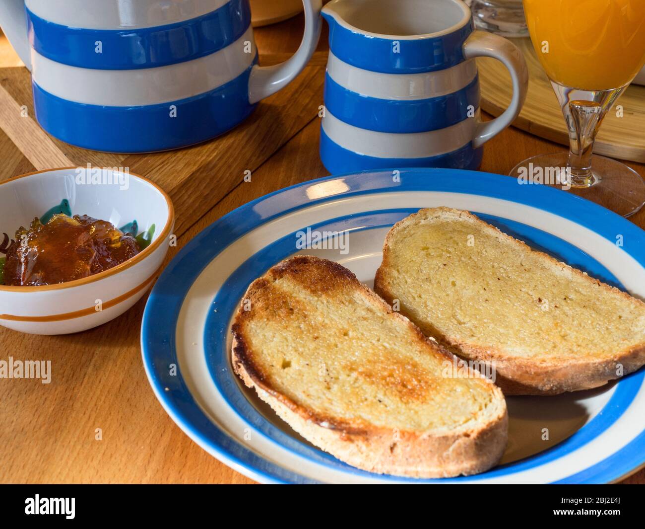 Holztisch mit Cornishware Service mit gerösteten gebutterten Haferbrot und Marmelade gelegt Stockfoto